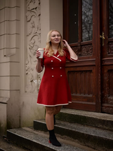 A blonde lady wears a double breasted dress